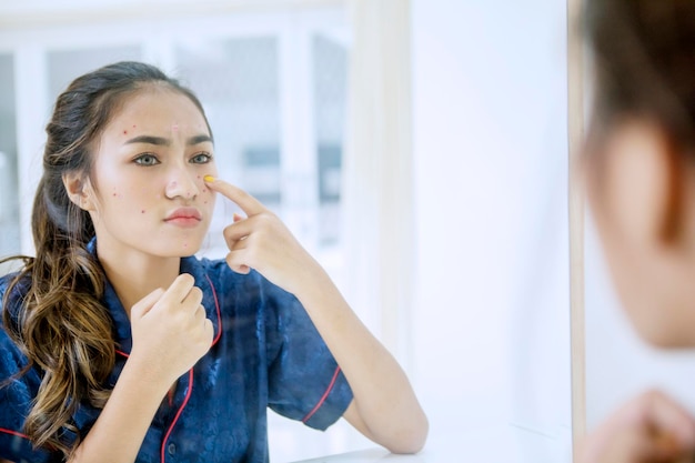 Une belle adolescente qui touche des boutons sur son visage