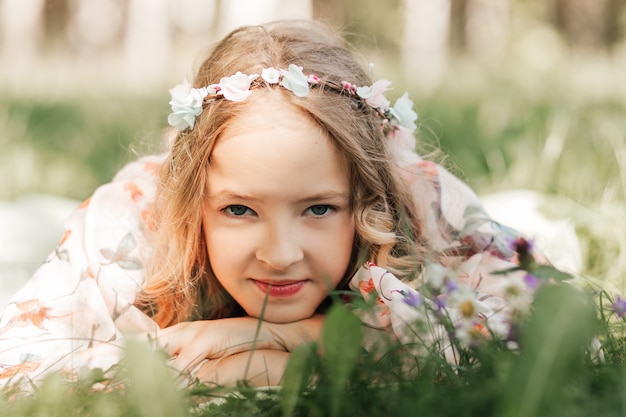 Une belle adolescente se trouve sur l'herbe. Regarder dans la caméra