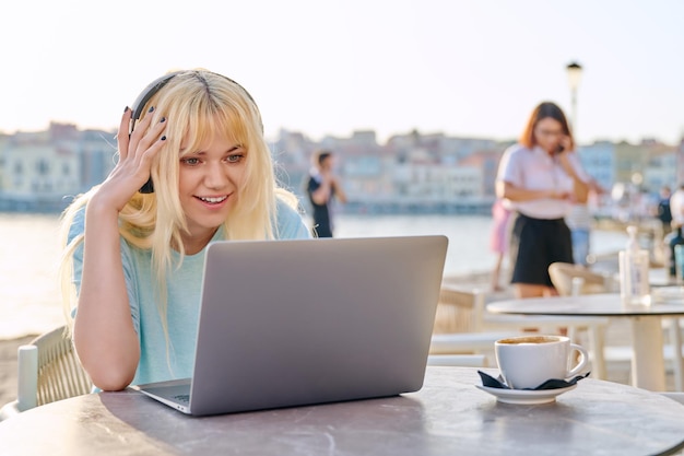 Belle adolescente souriante dans un casque regardant dans un ordinateur portable