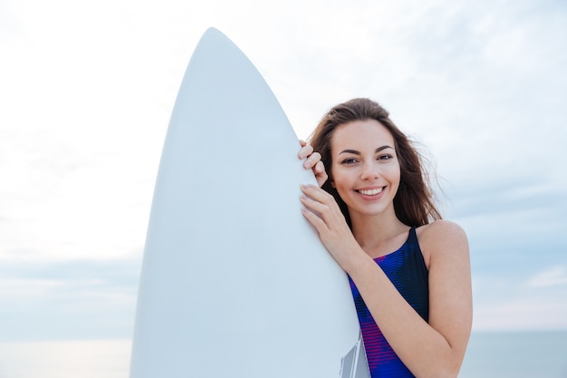 Belle adolescente de surfeur debout avec planche de surf à la plage