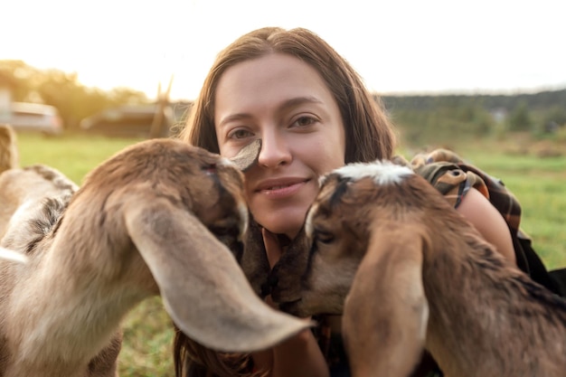 Belle agricultrice avec une petite chèvre à la campagne a de l'amitié dans la nature