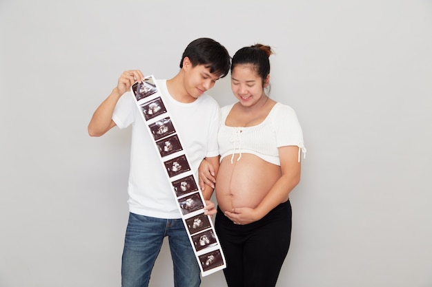 Belle asiatique mari et femme portrait famille heureuse attend un bébé sur un mur blanc