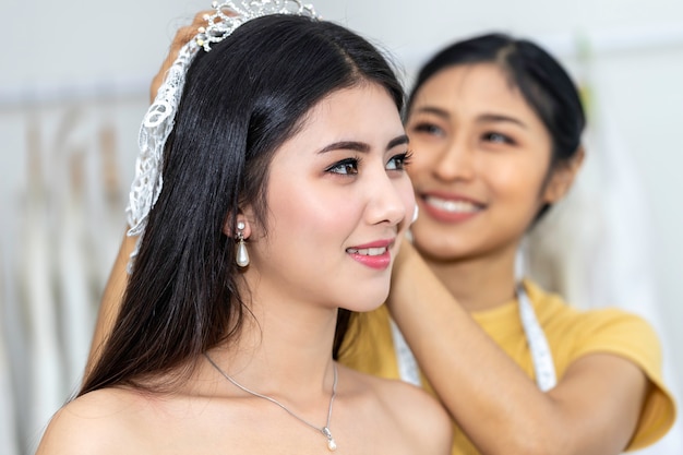 Belle asiatique souriante et essayant la robe de mariée dans un magasin.