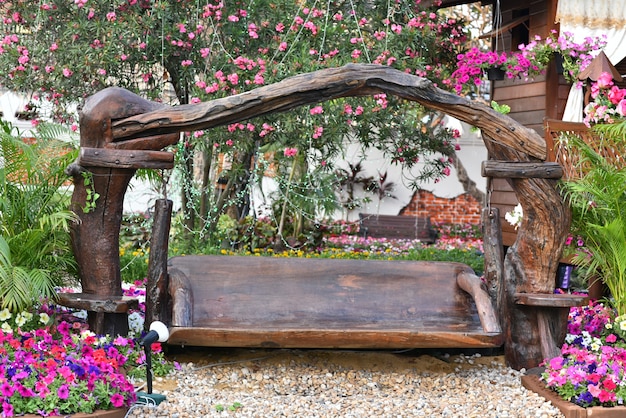 Belle assise en bois vintage dans le jardin de fleurs roses a rocher sur terre.