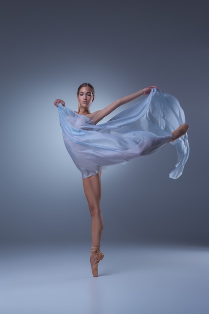 La belle ballerine dansant avec voile bleu sur fond bleu