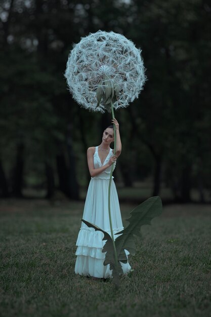 Photo belle ballerine avec des fleurs de pissenlits géantes