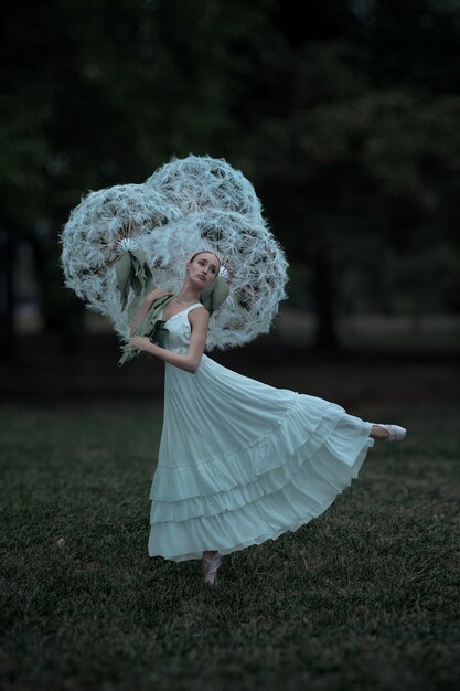 Photo belle ballerine avec des fleurs de pissenlits géantes