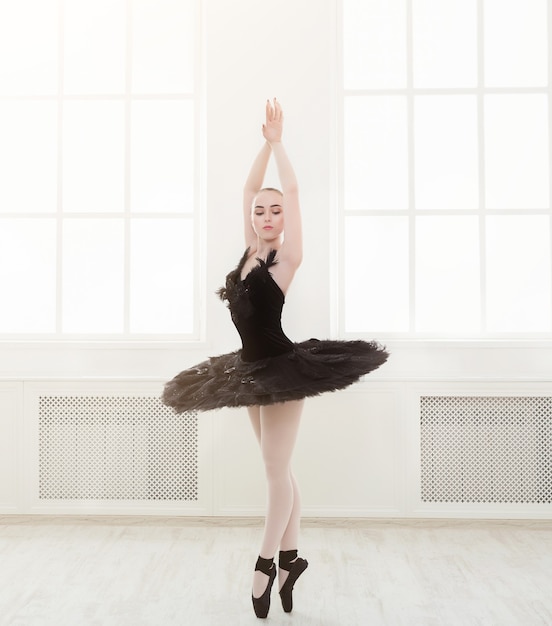 Belle ballerine gracieuse en robe de cygne noir. Jeune danseur de ballet pratiquant avant la représentation en tutu noir, studio de danse classique, espace de copie