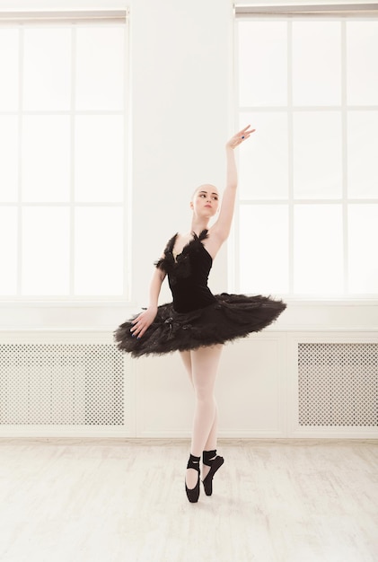 Belle ballerine gracieuse en robe de cygne noir. Jeune danseuse de ballet pratiquant avant la représentation en tutu noir, studio de danse classique, espace de copie