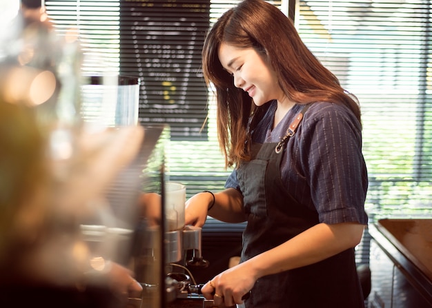 Belle barista sourit dans son café