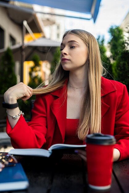 Une belle blonde aux cheveux charmants prend son petit-déjeuner dans un café à l'aide d'un ordinateur portable Concept d'entreprise