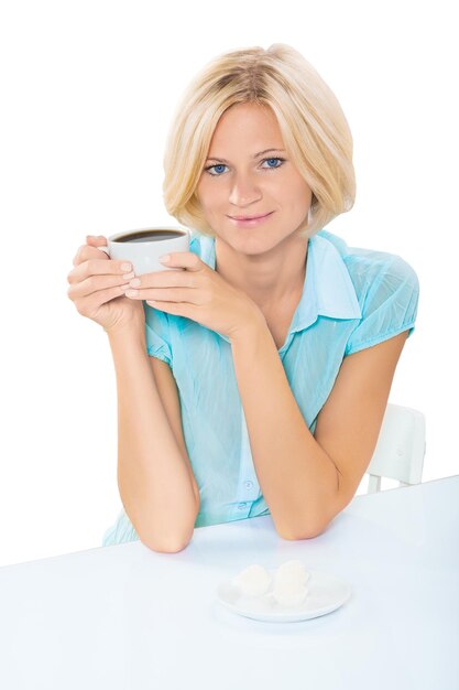 Belle blonde aux cheveux courts assis à la table avec une tasse de café isolé