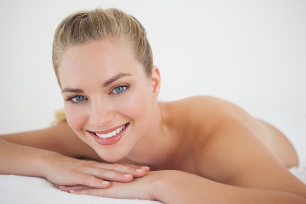 Belle blonde détente sur la table de massage, souriant à la caméra