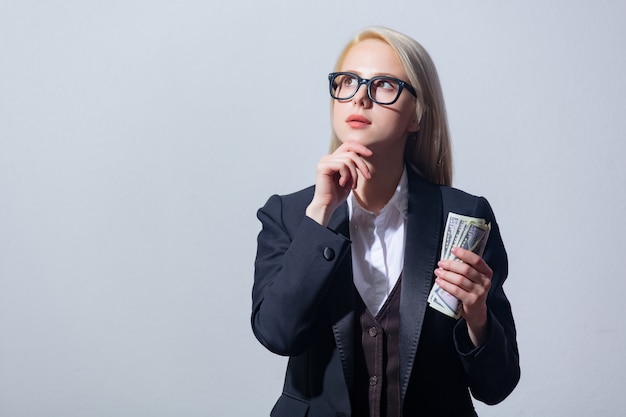 Belle blonde femme d'affaires en costume avec de l'argent sur fond gris