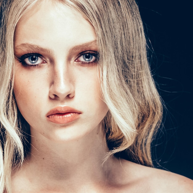 Belle blonde femme modèle de beauté fille avec un maquillage et une coiffure parfaits sur fond noir.