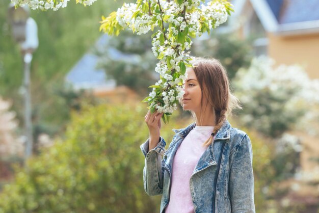 belle blonde sur la pelouse aime les arbres en fleurs et inhale leur parfum