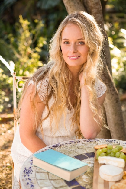 Belle blonde se détendre avec un livre et de la nourriture dans le jardin