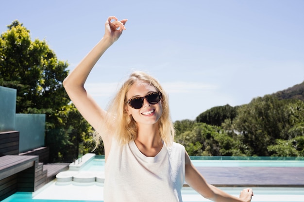 Belle blonde souriante à la caméra au bord de la piscine