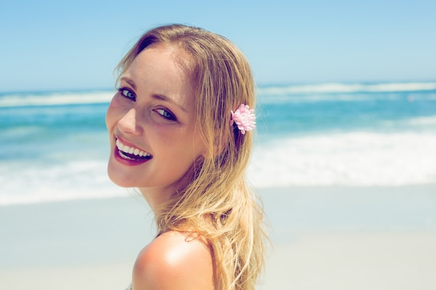 Belle blonde souriante à la caméra sur la plage