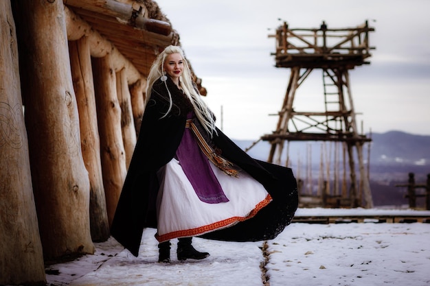 Belle blonde Viking vêtue d'un manteau noir sur fond de château