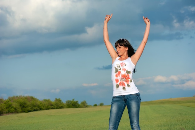 Une belle brune aux gros seins se dresse contre le ciel bleu dans un t-shirt blanc