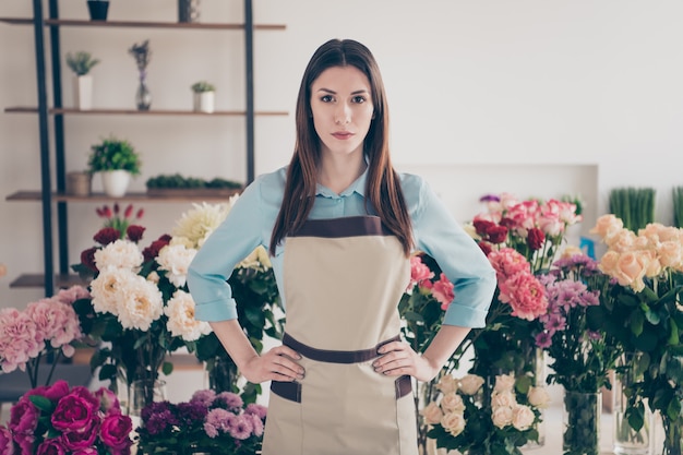 belle brune botaniste posant dans son magasin de fleurs