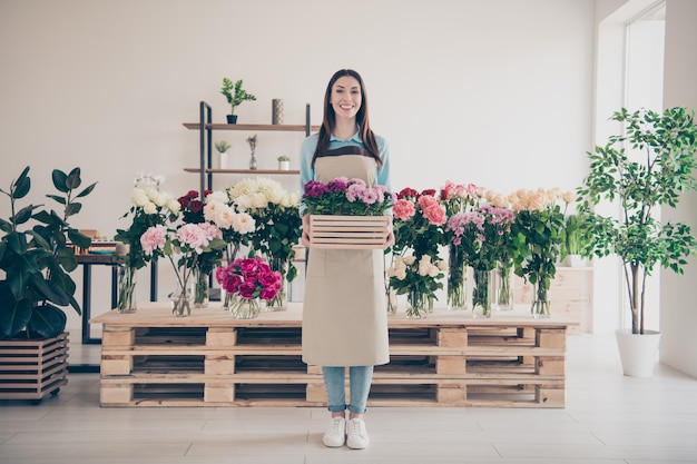 belle brune botaniste posant dans son magasin de fleurs