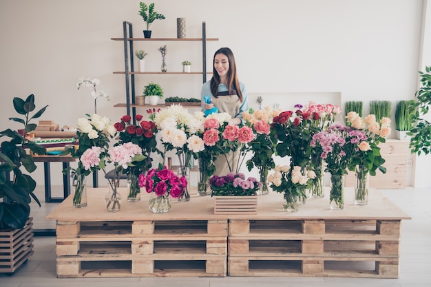 belle brune botaniste posant dans son magasin de fleurs