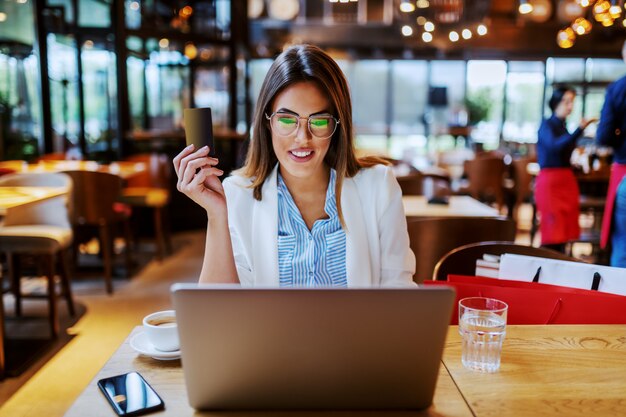 Belle brune charmante à la mode positive assis dans un café