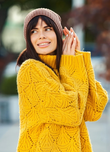 Belle brune européenne vêtue d'un pull en laine jaune et d'un chapeau à l'extérieur