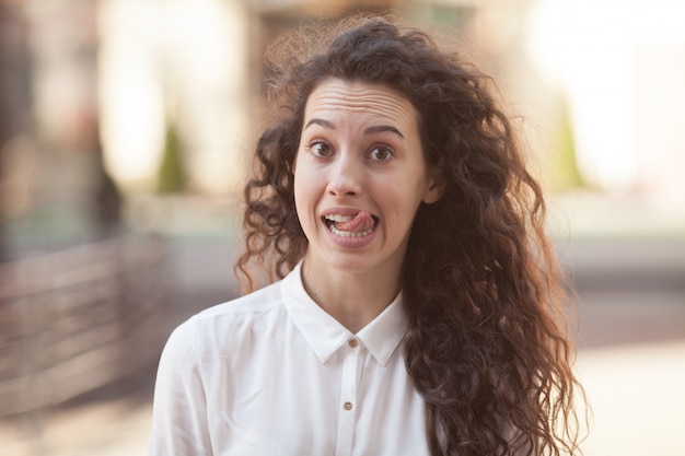 Belle brune femme bouclée, souriant à l'extérieur