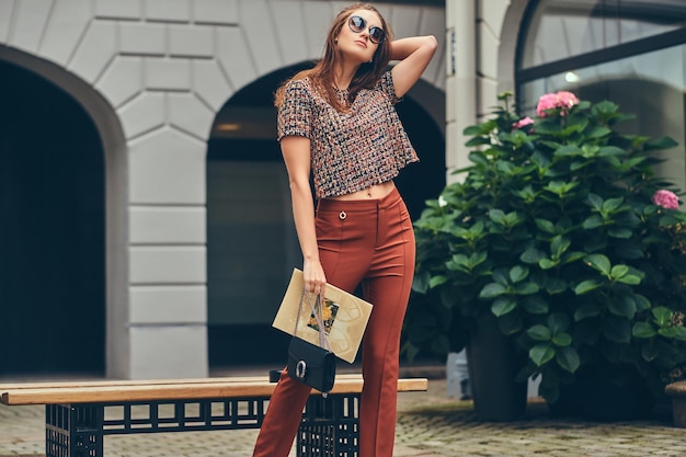 Belle brune à la mode portant des vêtements à la mode et des lunettes de soleil.