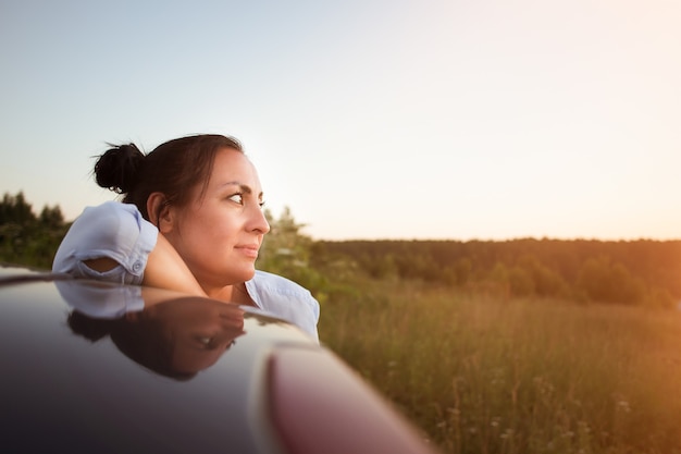 Photo belle brune regarde le coucher de soleil, gros plan.