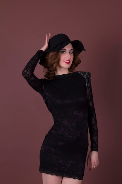 Belle brune en robe noire et chapeau