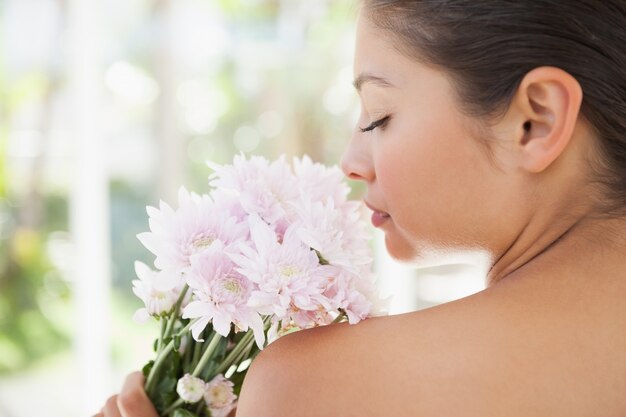 Belle brune sentant le bouquet de fleurs roses