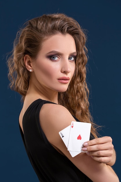 Belle brune tenant deux as comme signe pour le jeu de poker, le jeu et le casino