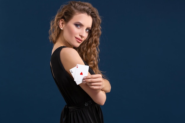 Belle brune tenant deux as comme signe pour le jeu de poker, le jeu et le casino