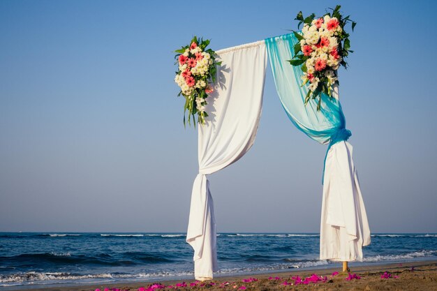 Belle cérémonie de mariage d'été à l'extérieur Arc de mariage en tissu léger et fleurs blanches et roses sur la mer