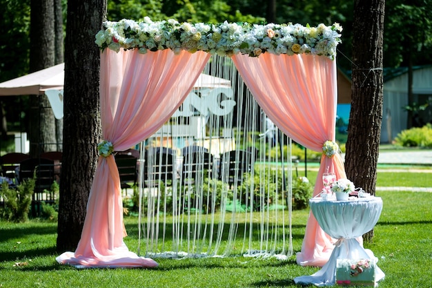 Belle cérémonie de mariage à l'extérieur Arc de mariage en tissu et fleurs blanches et roses sur fond de restaurant