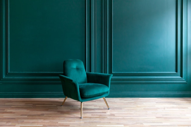 Belle chambre intérieure de luxe classique bleu vert propre dans un style classique avec fauteuil vert doux. Chaise bleu-vert antique vintage debout à côté d'un mur d'émeraude. Conception de maison minimaliste.