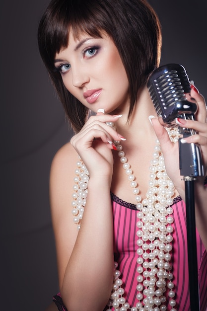 Belle chanteuse chantant avec un micro rétro en studio