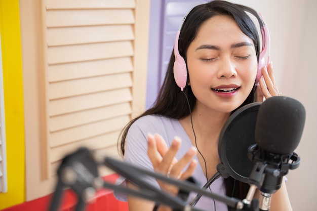 Une belle chanteuse portant des écouteurs avec des gestes de la main tout en écoutant une chanson