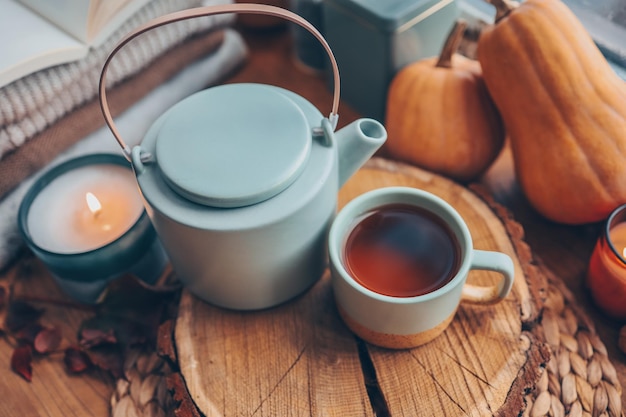 Belle composition d'automne avec des bougies allumées et une tasse de thé sur le rebord de la fenêtre