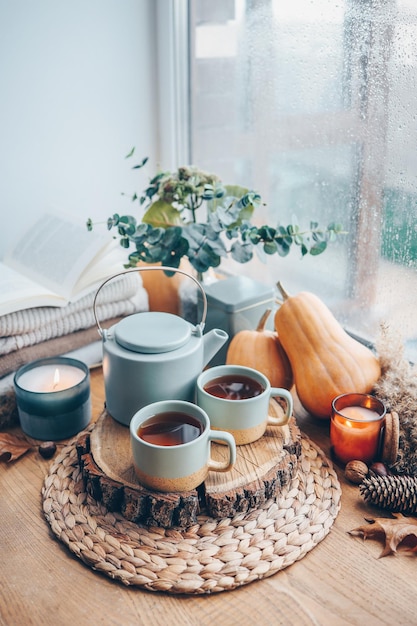 Belle composition d'automne avec des bougies allumées et une tasse de thé sur le rebord de la fenêtre