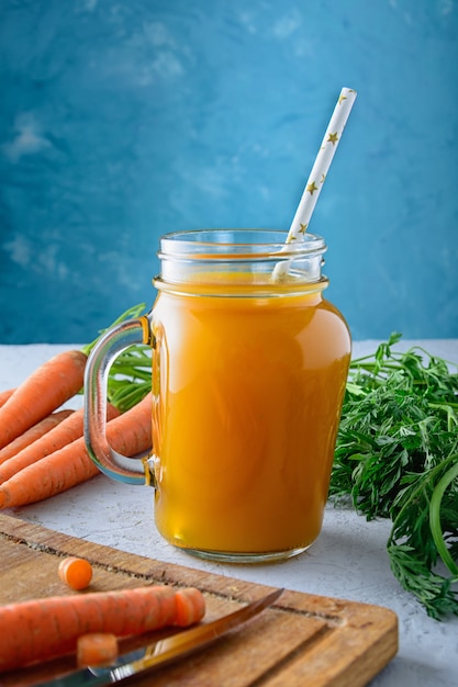 Belle composition avec une canette de jus de carotte avec une paille.