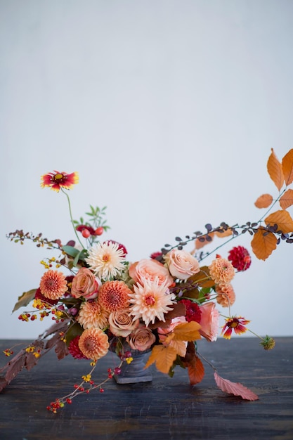 Belle composition de fleurs avec des fleurs et des baies orange et rouges d'automne Bouquet d'automne dans un vase vintage sur un fond de mur blanc