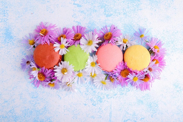 Belle composition avec macarons et fleurs sur fond bleu. Vue de dessus