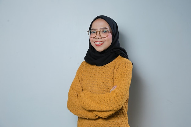 Belle et confiante jeune femme musulmane asiatique portant un pull orange et des lunettes