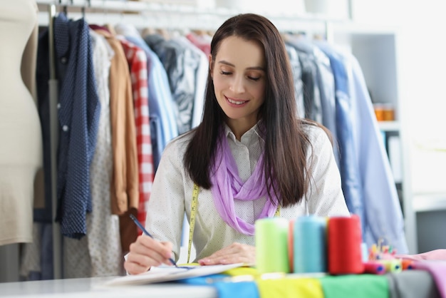 Une belle couturière dans l'atelier prend des notes