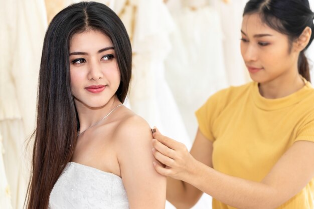 Belle Dame Asiatique Choisissant Robe Dans Un Magasin Avec Assistant Tailleur.